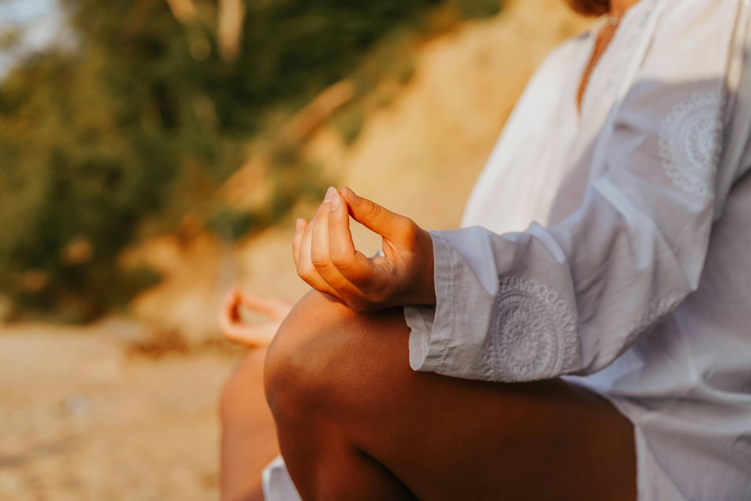 A close-up of a person meditating outdoors, capturing mindfulness at sunset on a beach.